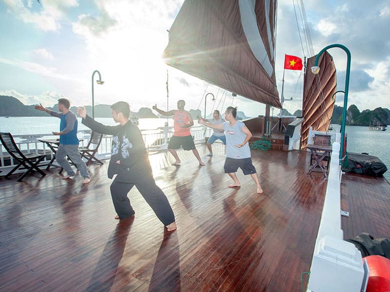 7 Best HaLong Bay Cruises for an Epic Journey 8 Passengers practicing tai chi on Bhaya Classic cruise deck