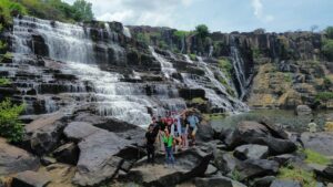 Pongour Waterfall in Da Lat, Vietnam, cascades over terraced rocks in summer, surrounded by green forest and morning mist, a top thing to do in Da Lat.